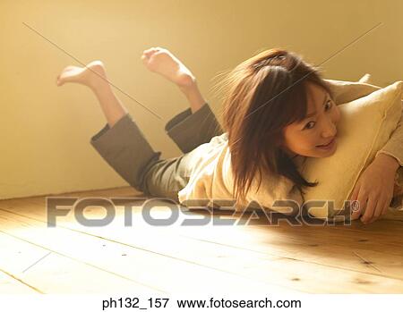 Young woman on floor with pillow View Large Photo Image Stock Photo - Young woman on floor with pillow. Fotosearch