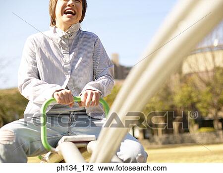 Young woman on seesaw View Large Photo Image Stock Image - Young woman on seesaw. Fotosearch