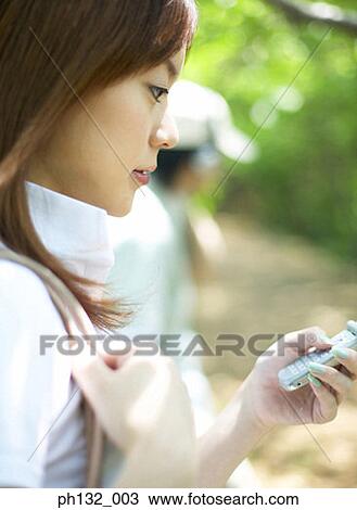 Stock Image - Young woman operating mobile phone. Fotosearch
