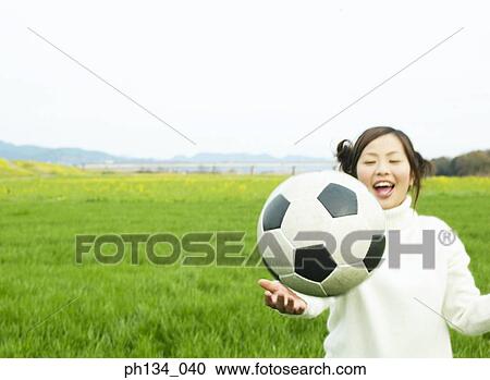 Stock Image - Young woman playing football. Fotosearch