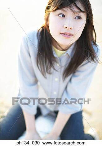 Young woman sitting and looking around View Large Photo Image Stock Image - Young woman sitting and looking around. Fotosearch