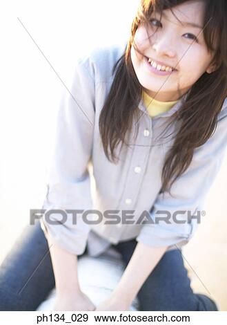 Young woman sitting and smiling View Large Photo Image Stock Photo - Young woman sitting and smiling. Fotosearch