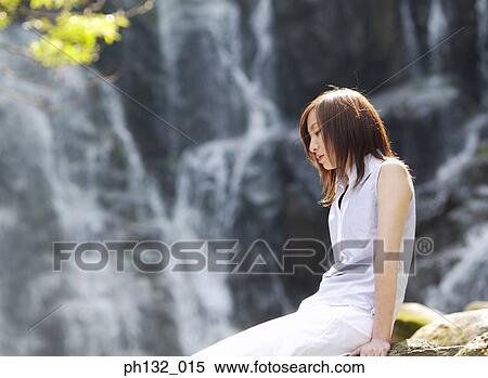 Young woman sitting by a waterfall View Large Photo Image Stock Photography - Young woman sitting by a waterfall. Fotosearch