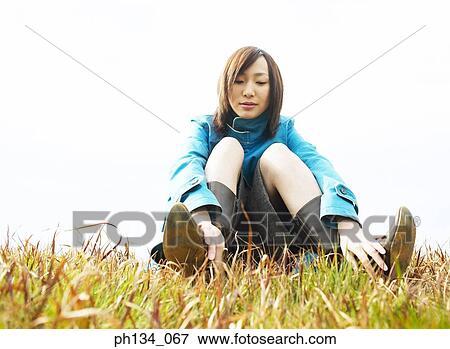 Young woman sitting on grass View Large Photo Image Stock Photo - Young woman sitting on grass. Fotosearch
