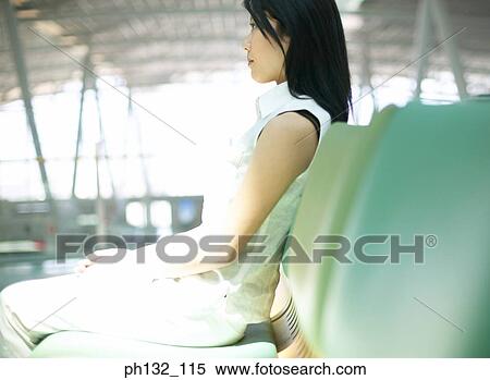 Stock Photography - Young woman sitting on sofa seat. Fotosearch