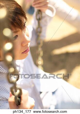 Young woman sitting on swing View Large Photo Image Stock Photo - Young woman sitting on swing. Fotosearch