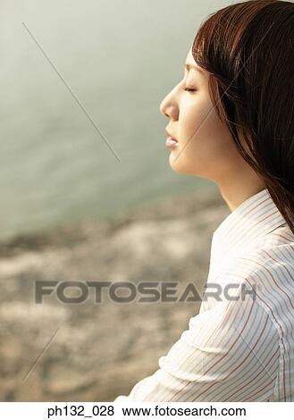 Young woman sitting with eyes closed View Large Photo Image Stock Photo - Young woman sitting with eyes closed. Fotosearch