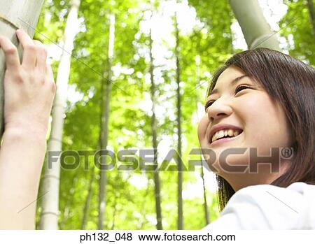 Young woman standing in a bamboo plantation smiling View Large Photo Image Stock Photo - Young woman standing in a bamboo plantation smiling. Fotosearch