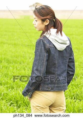 Young woman standing in field View Large Photo Image Picture - Young woman standing in field. Fotosearch