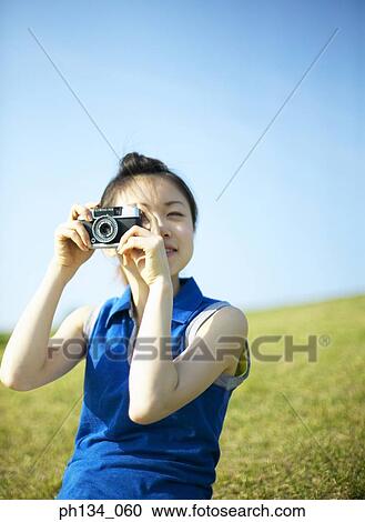 Stock Image - Young woman taking a photograph. Fotosearch