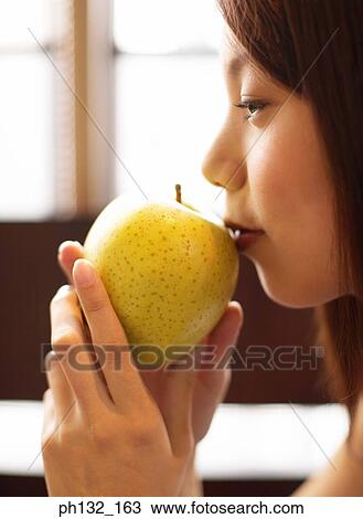 Young woman with an apple to her mouth View Large Photo Image Stock Image - Young woman with an apple to her mouth. Fotosearch