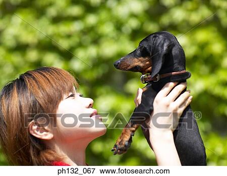 Young women holding up pet dog View Large Photo Image Stock Photo - Young women holding up pet dog. Fotosearch