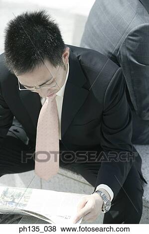 High angle view of a young businessmen reading the papers View Large Photo Image Stock Photo - High angle view of a young businessmen reading the papers. Fotosearch