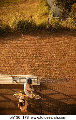 High angle view of a young couple walking with a bicycle View Large Photo Image Stock Photo - High angle view of a young couple walking with a bicycle. Fotosearch
