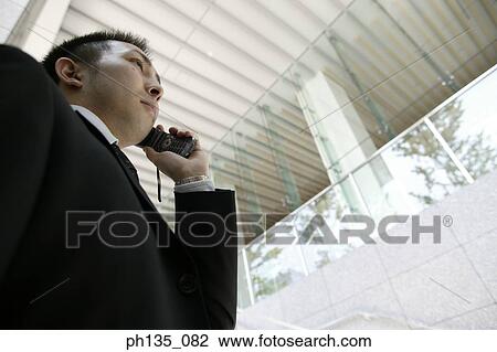 Low angle view of a young businessman using a mobile phone View Large Photo Image Stock Image - Low angle view of a young businessman using a mobile phone. Fotosearch
