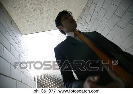 Low angle view of a young businessman coming down a flight of stairs View Large Photo Image Stock Photo - Low angle view of a young businessman coming down a flight of stairs. Fotosearch