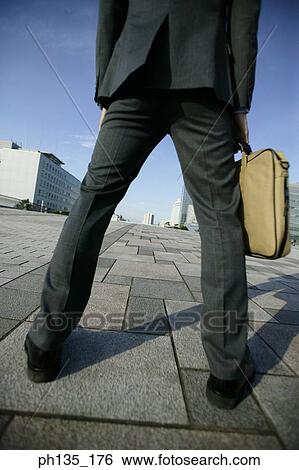 Low angle view of a young businessman holding a briefcase View Large Photo Image Stock Photograph - Low angle view of a young businessman holding a briefcase. Fotosearch