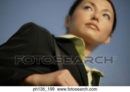Stock Photo - Low angle view of a young businesswoman carrying a shoulder bag. Fotosearch