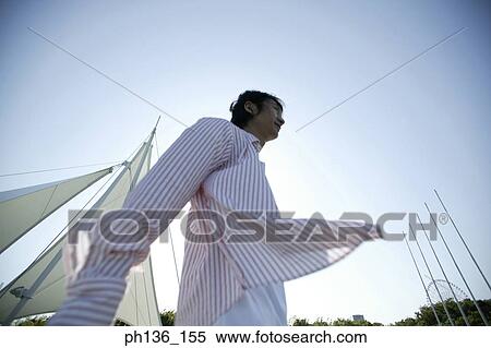 Low angle view of a young man walking View Large Photo Image Stock Photography - Low angle view of a young man walking. Fotosearch
