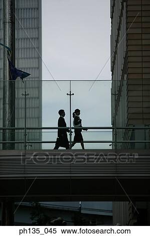 Low angle view of two executives walking on a bridge View Large Photo Image Stock Photography - Low angle view of two executives walking on a bridge. Fotosearch