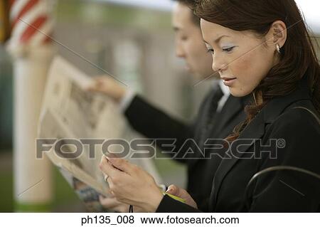 Side profile of young business executives waiting on a station View Large Photo Image Stock Photo - Side profile of young business executives waiting on a station. Fotosearch