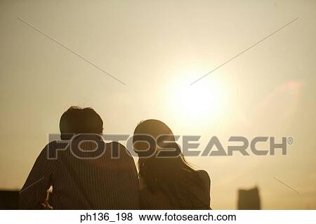Stock Photo - Silhouette of a young couple standing looking down. Fotosearch