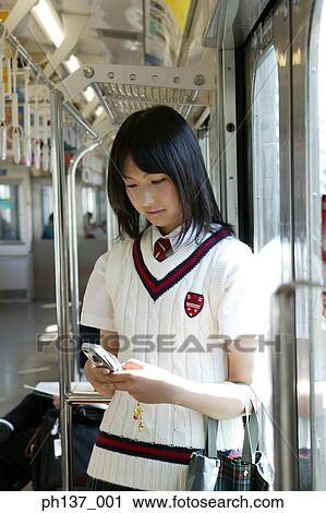 Teenage girl operating a mobile phone in a train View Large Photo Image Stock Image - Teenage girl operating a mobile phone in a train. Fotosearch
