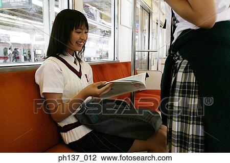 Stock Image - Teenage girl sitting in a train Reading a Book. Fotosearch