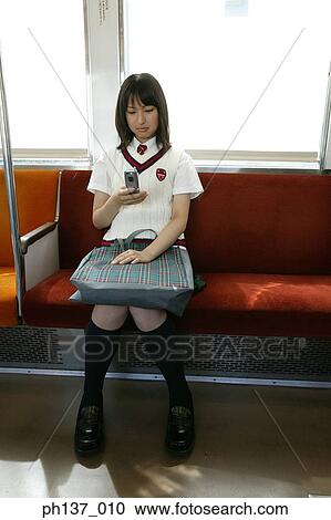 Teenage girl sitting in a train operating a mobile phone View Large Photo Image Stock Image - Teenage girl sitting in a train operating a mobile phone. Fotosearch