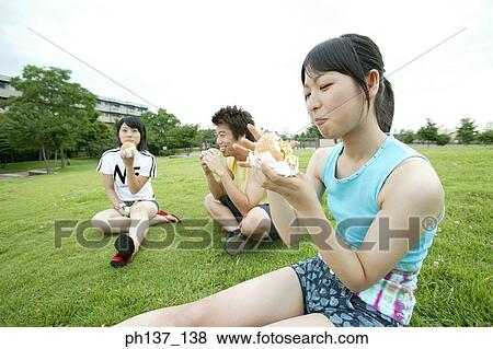Teenagers sitting on a lawn eating hamburgers View Large Photo Image Stock Photo - Teenagers sitting on a lawn eating hamburgers. Fotosearch
