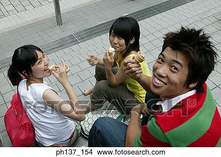 Teenagers sitting together eating ice cream View Large Photo Image Picture - Teenagers sitting together eating ice cream. Fotosearch