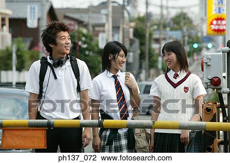 Stock Image - Teenagers standing and waiting at a railway crossing. Fotosearch
