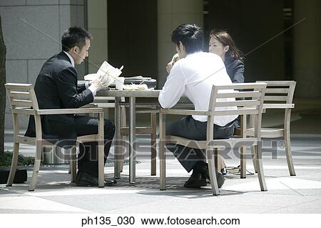 Three colleagues having lunch at an outdoor cafe View Large Photo Image Stock Image - Three colleagues having lunch at an outdoor cafe. Fotosearch