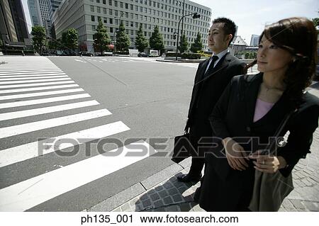 Stock Image - Young business executives waiting on a sidewalk. Fotosearch