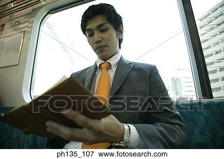 Young businessman reading a book in the train View Large Photo Image Stock Photo - Young businessman reading a book in the train. Fotosearch