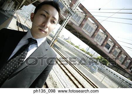 Young businessman standing at a train station View Large Photo Image Stock Photo - Young businessman standing at a train station. Fotosearch