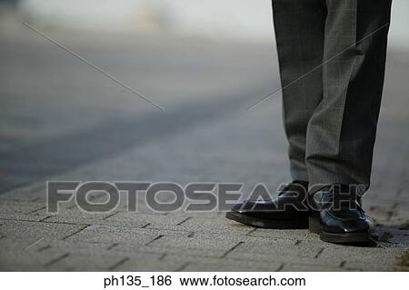 Young businessman standing on the sidewalk View Large Photo Image Stock Photograph - Young businessman standing on the sidewalk. Fotosearch