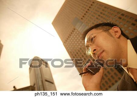 Young businessman talking on a mobile phone View Large Photo Image Stock Image - Young businessman talking on a mobile phone. Fotosearch