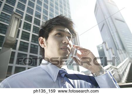Stock Photo - Young businessman talking on a mobile phone. Fotosearch
