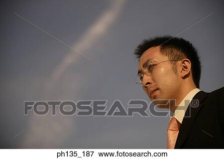 Young businessman wearing eye glasses looking ahead View Large Photo Image Stock Photo - Young businessman wearing eye glasses looking ahead. Fotosearch