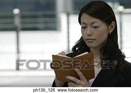Stock Photograph - Young businesswoman holding a diary. Fotosearch