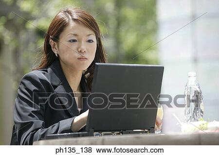 Young businesswoman operating a laptop computer View Large Photo Image Stock Photo - Young businesswoman operating a laptop computer. Fotosearch
