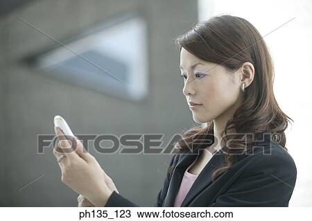 Stock Image - Young businesswoman operating a mobile phone. Fotosearch