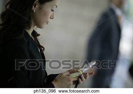 Stock Photograph - Young businesswoman operating a mobile phone. Fotosearch
