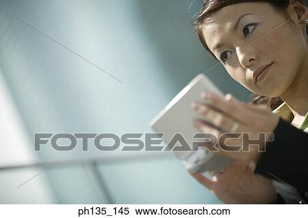 Stock Photography - Young businesswoman operating a handheld device. Fotosearch