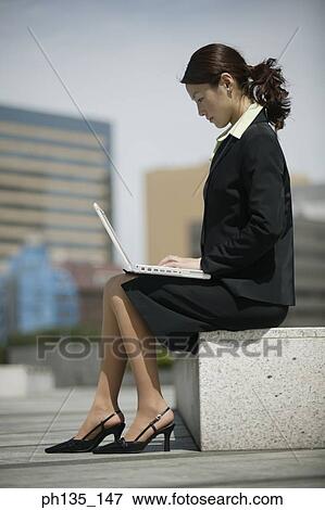 Young businesswoman sitting operating a laptop computer View Large Photo Image Stock Photo - Young businesswoman sitting operating a laptop computer. Fotosearch