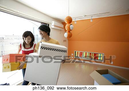 Stock Image - Young couple carrying boxes. Fotosearch