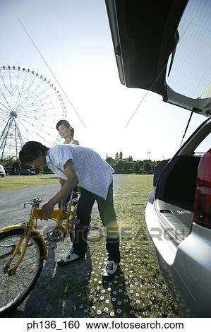 Stock Image - Young couple holding a bicycle. Fotosearch