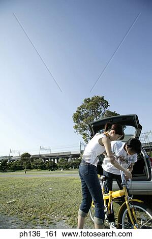 Stock Image - Young couple holding a bicycle. Fotosearch