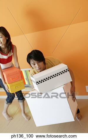 Stock Image - Young couple holding boxes. Fotosearch